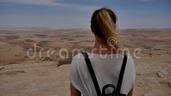戴墨镜的年轻女子在悬崖边欣赏石漠景色视频的预览图