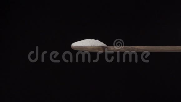 盐从上面倒入一个木勺隔离在黑色的背景上厨房概念视频的预览图