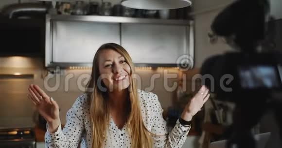 快乐年轻美丽的美食博主女人用专业相机在厨房慢动作拍摄新的vlog视频视频的预览图