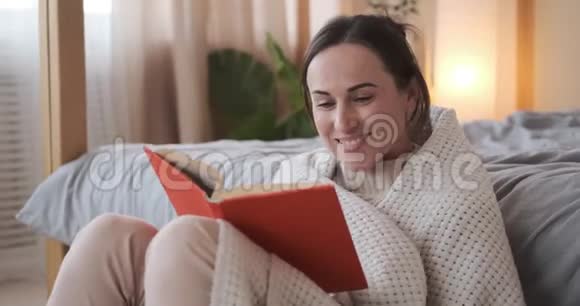 快乐的女人用毯子包着看书视频的预览图