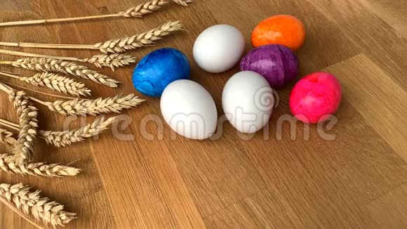 彩色彩蛋和麦穗躺在木桌上复活节的概念视频的预览图