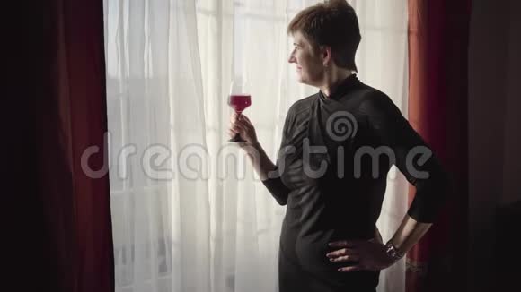 高级漂亮的白种人女士站在阳光下喝着一杯酒看着窗户成熟的商人视频的预览图