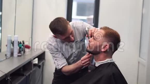 巴伯把客户胡子剃在椅子上胡子的发型用电动剃须刀刮胡子装饰视频的预览图