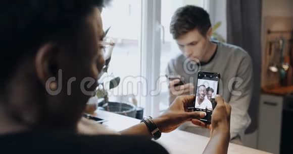 特写幸福的年轻微笑的黑人夫妇在厨房自拍智能手机孤独的朋友用手机慢动作视频的预览图