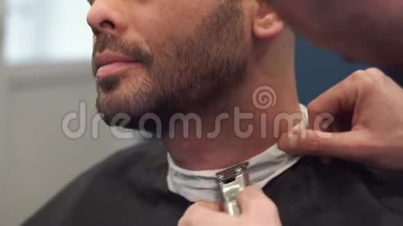 巴伯把客户胡子剃在椅子上胡子的发型用电动剃须刀刮胡子装饰视频的预览图