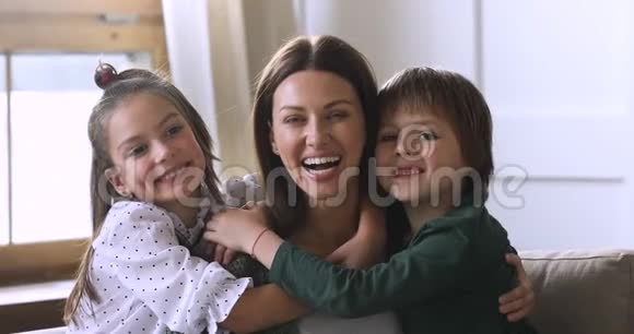 可爱的妈妈和可爱的孩子们拥抱着笑看着摄像机视频的预览图