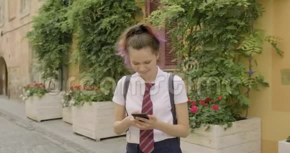 漂亮的学生少年女孩有智能手机读写短信视频的预览图