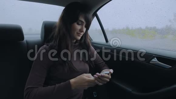 雨天坐在车里用智能手机的女人视频的预览图