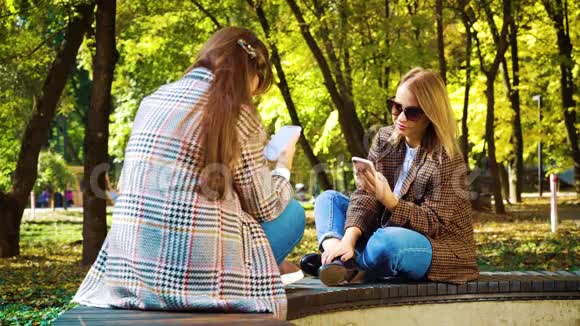 坐在秋园里用智能手机应用的可爱女孩视频的预览图