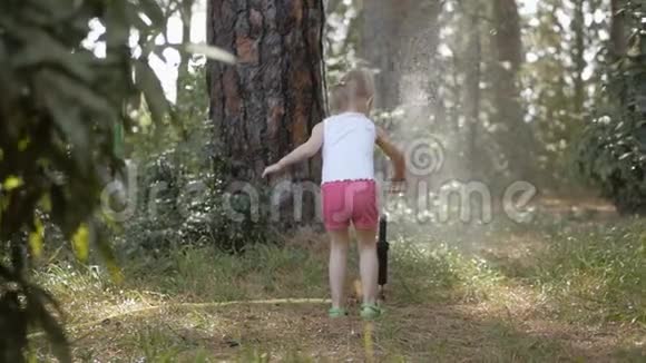 在城市公园里一个小女孩在水流下玩草坪洒水器视频的预览图