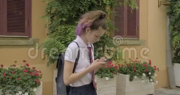 漂亮的学生少年女孩有智能手机读写短信视频的预览图