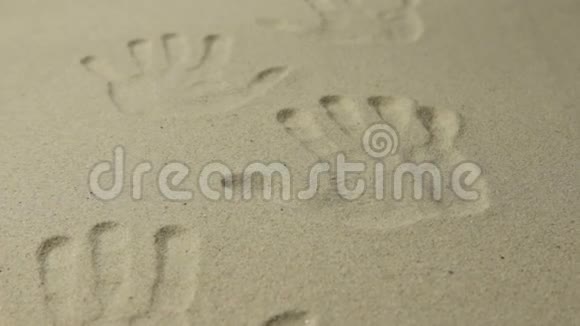 许多人的手印在沙子上作为背景缩放视频的预览图