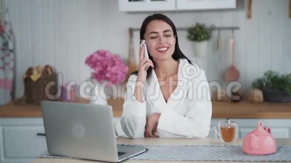 美丽的女人打电话早上坐在厨房视频的预览图