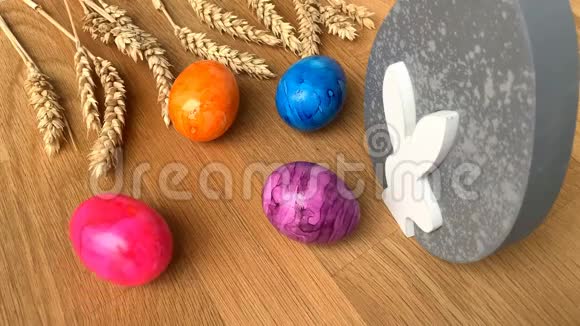 彩色彩蛋和麦穗躺在木桌上复活节的概念视频的预览图