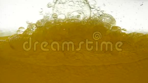 黄金精炼植物油在白色移动的背景下慢慢搅拌形成空气的气泡结构视频的预览图