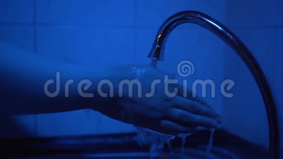 一个女人洗手是为了破坏微生物和防止病毒在深蓝色的灯光下洗手视频的预览图