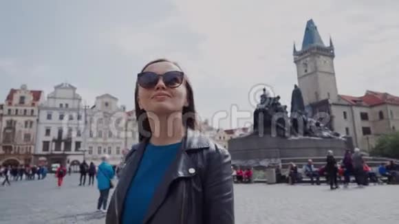 时尚的年轻女孩戴着太阳镜在捷克共和国布拉格老城广场散步上面有简胡斯纪念碑视频的预览图