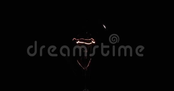 一个旧灯泡的闪光螺旋黑色背景上的钨丝视频的预览图