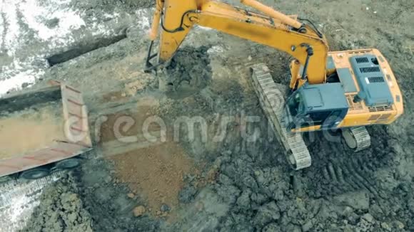 挖掘机正在收集泥土把它倒进卡车里视频的预览图
