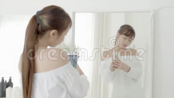 美丽的肖像年轻的亚洲女人站在卧室里用智能手机镜子自拍视频的预览图
