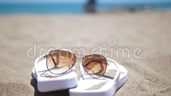 沙滩沙滩上戴太阳镜的白色拖鞋运动员在背景下奔跑视频的预览图