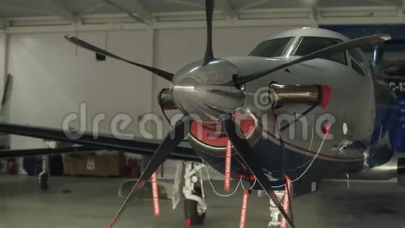 停在机库里的私人螺旋桨飞机在后台工作的技师视频的预览图