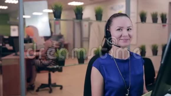 古怪的女人在一间干净明亮的办公室里用耳机说话呼叫中心视频的预览图