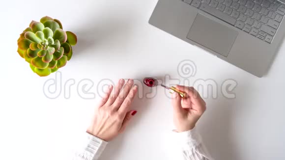 时光流逝商务女性在办公室工作场所用笔记本电脑涂红指甲油指甲护理和指甲护理平躺着4K视频的预览图