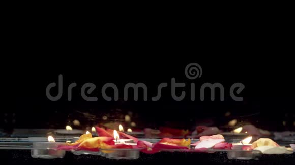 漂浮在水面和玫瑰花瓣上的蜡烛视频的预览图
