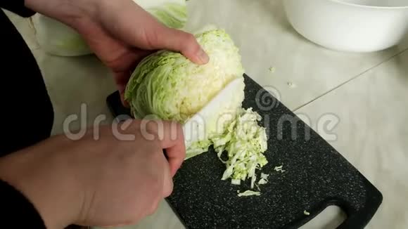 女人用刀子在木板上切一棵绿色的卷心菜把切菜的刀切成沙拉食物视频的预览图