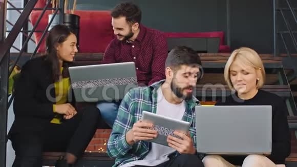 有魅力的年轻学生在大学楼梯上休息用平板电脑分析作业视频的预览图