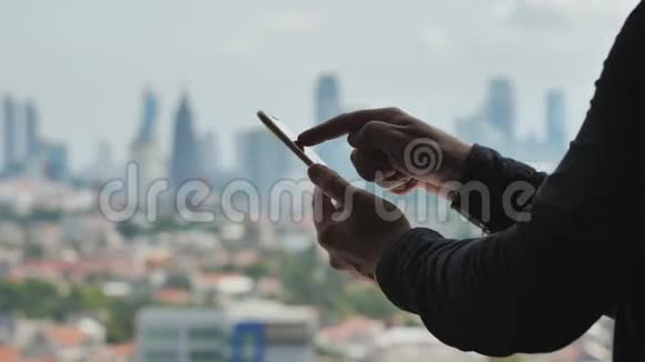 一个男人在智能手机上拨一条信息背景是雅加达市的全景加速录像视频的预览图