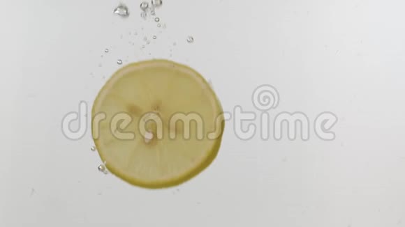 慢动作新鲜的柠檬片掉进水里白色背景上有飞溅和气泡视频的预览图