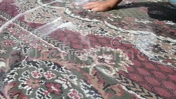 一个女人正在街上刷脏地毯在院子里的房子里关门用清水冲洗干净视频的预览图