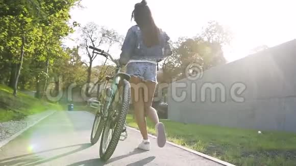 从年轻女子的背影看夏日骑自行车在城市街道上行走视频的预览图
