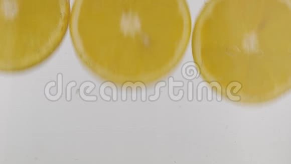 慢动作新鲜的橙片掉进水中白色背景上有飞溅和气泡视频的预览图
