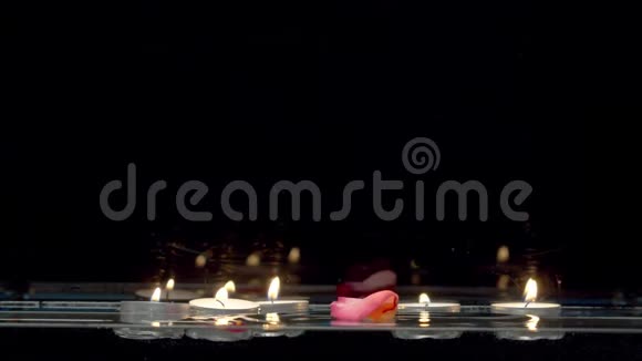 浮在水面上的蜡烛和落下的玫瑰花瓣视频的预览图