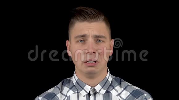 那个年轻人在哭情绪化的男人在黑色背景特写镜头上哭泣视频的预览图
