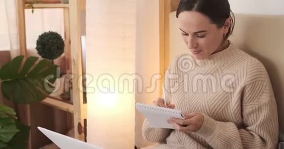 家里用笔记本电脑写笔记的女人视频的预览图
