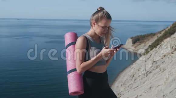 穿着运动服带垫子的女运动员在电话上发信息海在后台视频的预览图