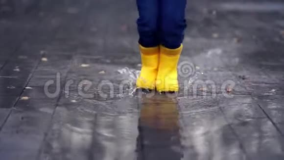 穿着黄色胶靴的快乐童腿在小水坑里跳舞跳视频的预览图