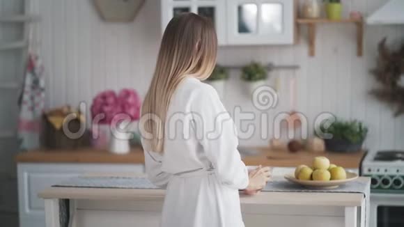 厨房里的年轻女人喝茶把杯子放在桌子上拿苹果视频的预览图