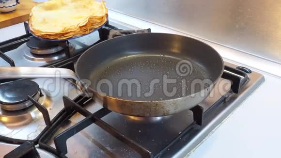一只手把面糊倒入一个热锅里煤气炉上有一个金属桶烤薄饼的过程视频的预览图
