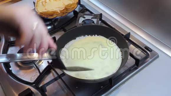 一只手在一个热气腾腾的煎锅里用塑料铲子把煎饼翻过来视频的预览图