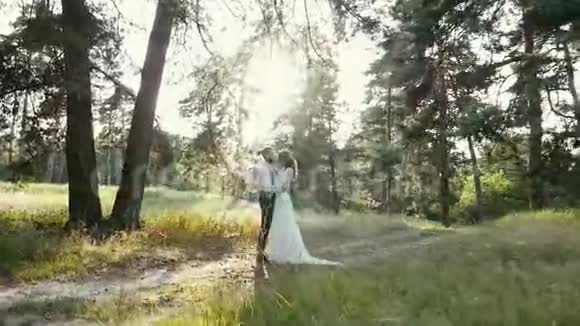 年轻漂亮的夫妇在森林里拥抱亲吻和微笑视频的预览图