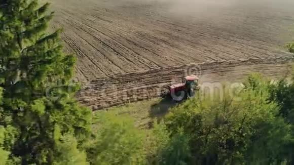 空中一种红色的工作拖拉机犁在路边的种植物后面种植加工土壤视频的预览图