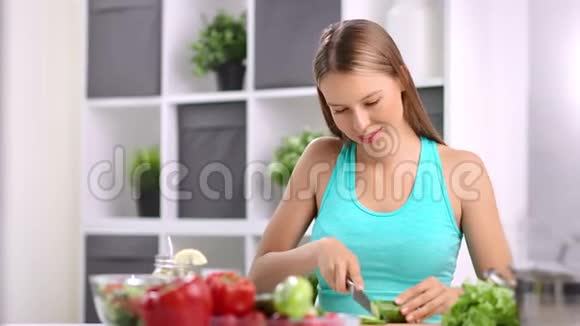 热心的年轻家庭主妇在家厨房里切黄瓜做蔬菜沙拉视频的预览图