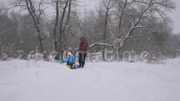 幸福的家庭观念圣诞节假期家庭在冬季公园玩耍爸爸和女儿在他们的妈妈的雪橇上视频的预览图