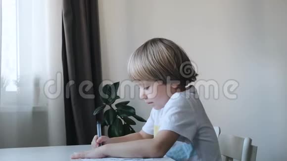 小男孩孩子坐在家里的桌子旁画画妈妈亲吻拥抱他视频的预览图
