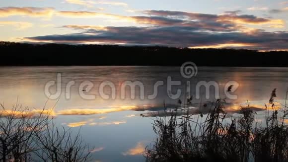 在橙色的夕阳下冰和树木在池塘上的云时间流逝捷克景观视频的预览图